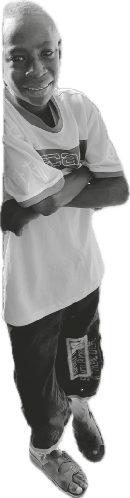 Black-and-white portrait of a smiling child standing with arms crossed. The child has very short hair and wears a loose T-shirt, dark pants with a patch on one leg, and open-toe sandals. They are leaning slightly to one side with one foot crossed in front of the other, facing the camera with a relaxed, confident expression. The image is cut out from the background, leaving the figure isolated against a transparent or plain backdrop.